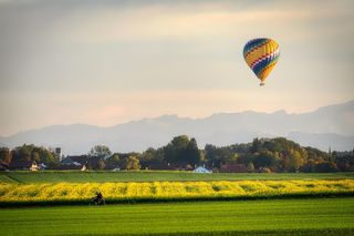 hot air balloon in field with mountain backdrop