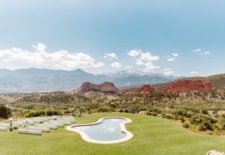 Wedding ceremony seats and arch setup outside on greens with a nearby pool and moutain views in the background.