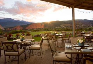 Dining tables and chairs outside with sunset views and stunning mountain views at Garden of the Gods Resort and Club.