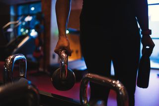 Close-up of an arm picking up a dumbbell.