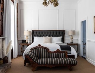 A rustic bedroom featuring a bed, a chair, and a fireplace.