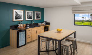 Suite kitchen bar with island and stools facing a teal wall background.
