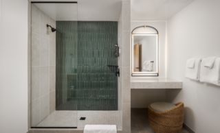 Bright and light queen suite bathroom featuring mirror, sink, and glass shower with teal backsplash.