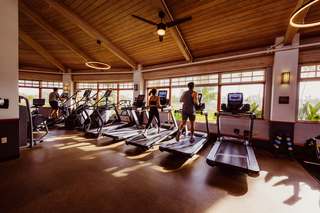 People running on treadmills in a gym filled with natural lighting and wood interior.