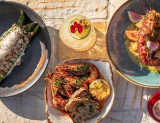 Overhead shot of a table laden with various tapas-style dishes on colorful, patterned tablecloth.